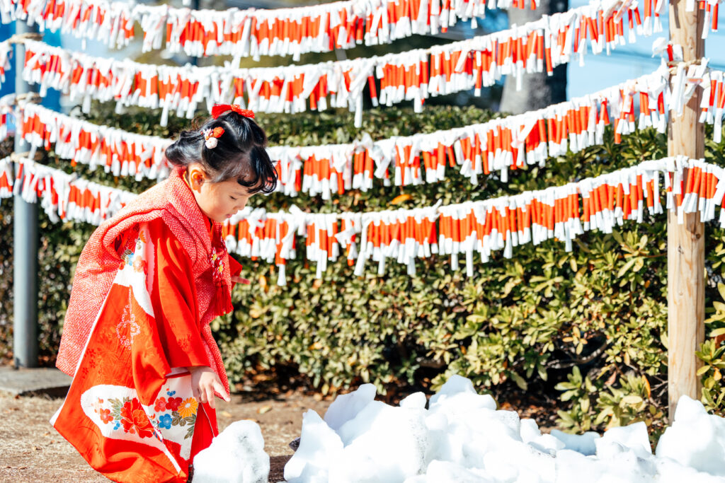 七五三で雪を触っている女の子の写真
